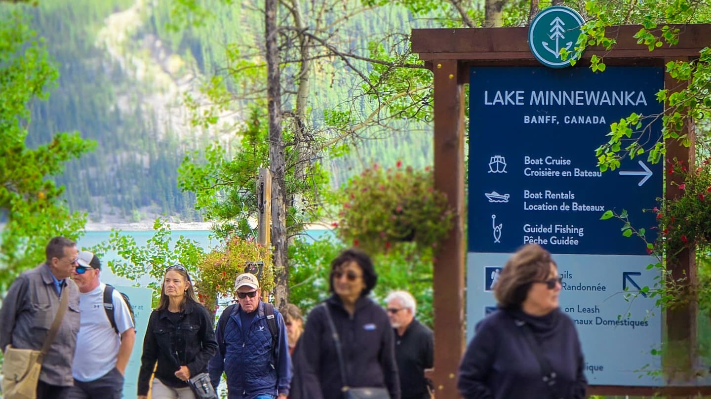 Visitors walking past the Lake Minnewanka trailhead sign near Banff